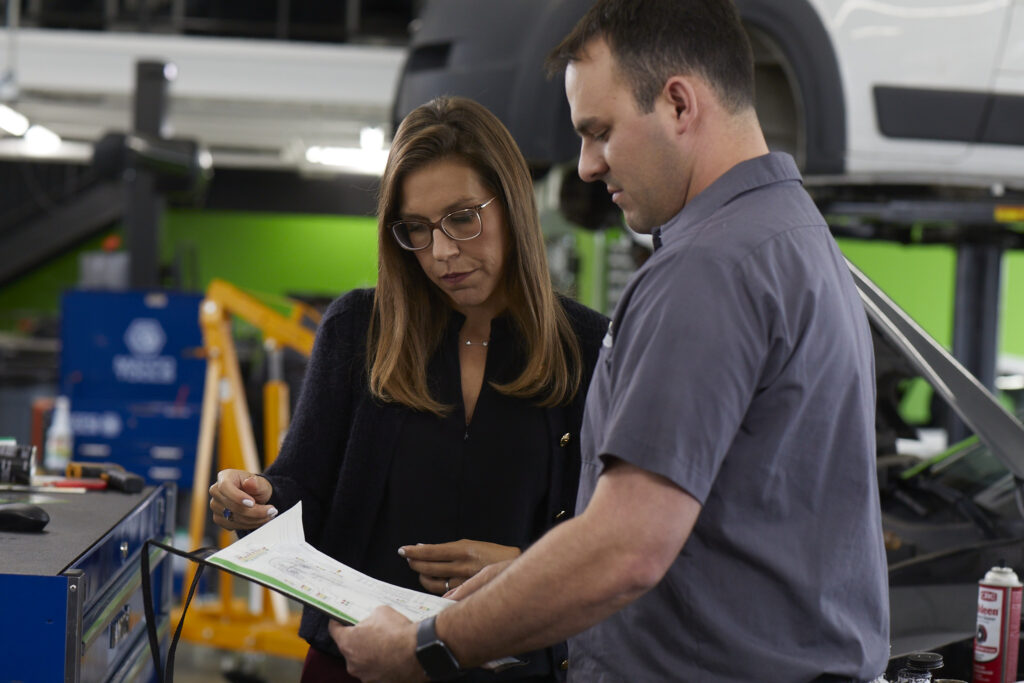 Julie Holmes looks at an automotive report with a male vehicle technician
